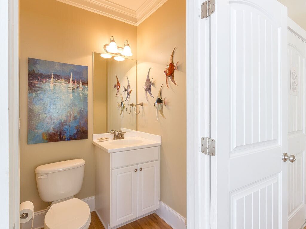 Ein Badezimmer mit Toilette, Waschbecken und Spiegel. Ein Bild hängt an der Wand und auf dem Spiegel sind dekorative Fische zu sehen.