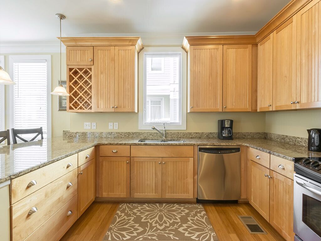 A kitchen with wooden cabinets, a stainless steel dishwasher, and a granite countertop.
