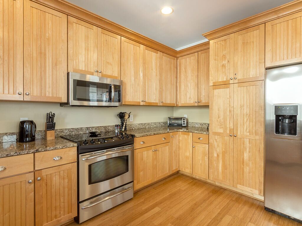 A kitchen with wooden cabinets, stainless steel appliances, granite countertops, and a built-in microwave.