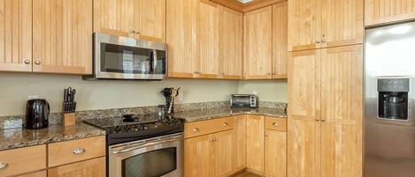 A kitchen with wooden cabinets, stainless steel appliances, granite countertops, and a built-in microwave.