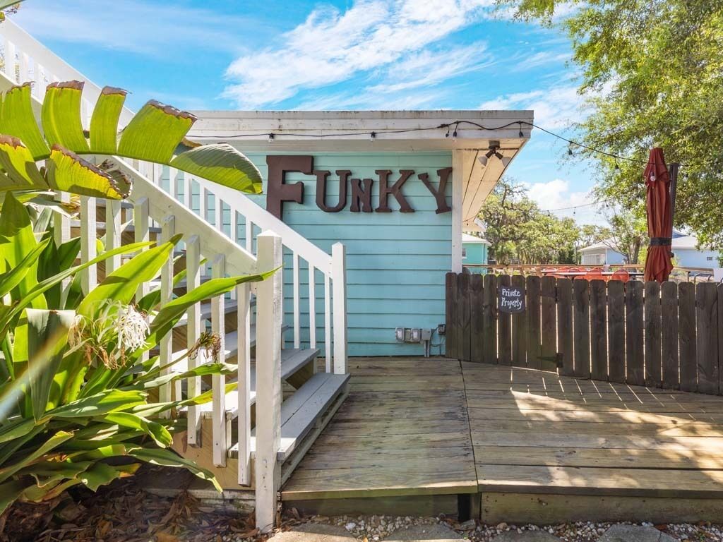 A wooden deck leading to a house with a sign that reads "FUNKY".