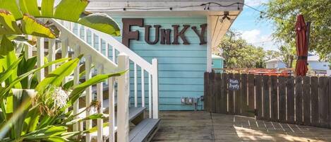 Una terraza de madera que conduce a una casa con un letrero que dice "FUNKY".