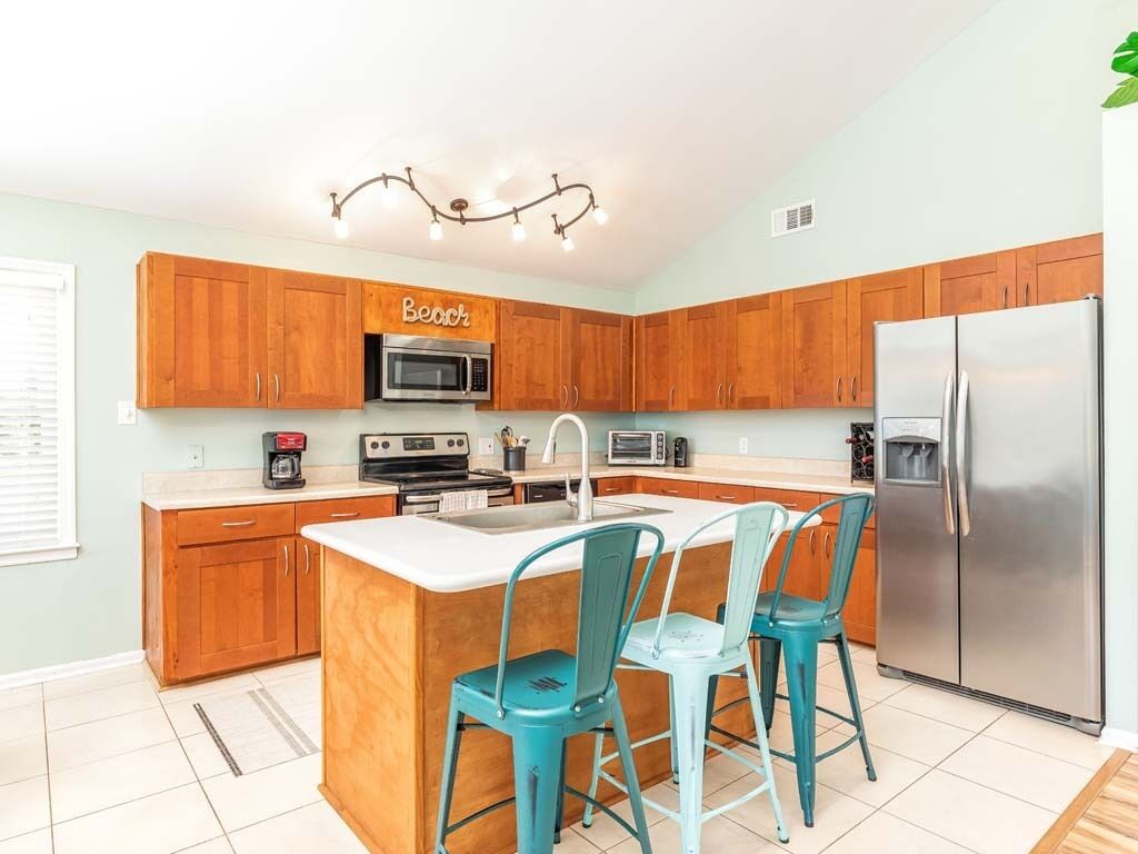 Una cocina con gabinetes de madera, un refrigerador de acero inoxidable, un microondas y una cafetera.