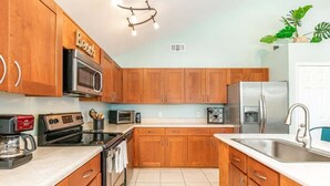 A kitchen with wooden cabinets, stainless steel appliances, and a white countertop. - All Decked Out by Tybee Vacation Rentals (Tybee Island)