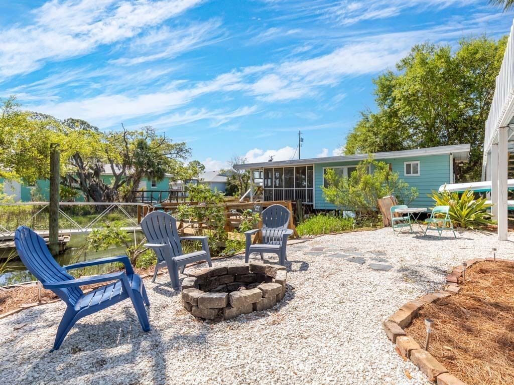 A patio area with Adirondack chairs, a fire pit, and a view of a house.