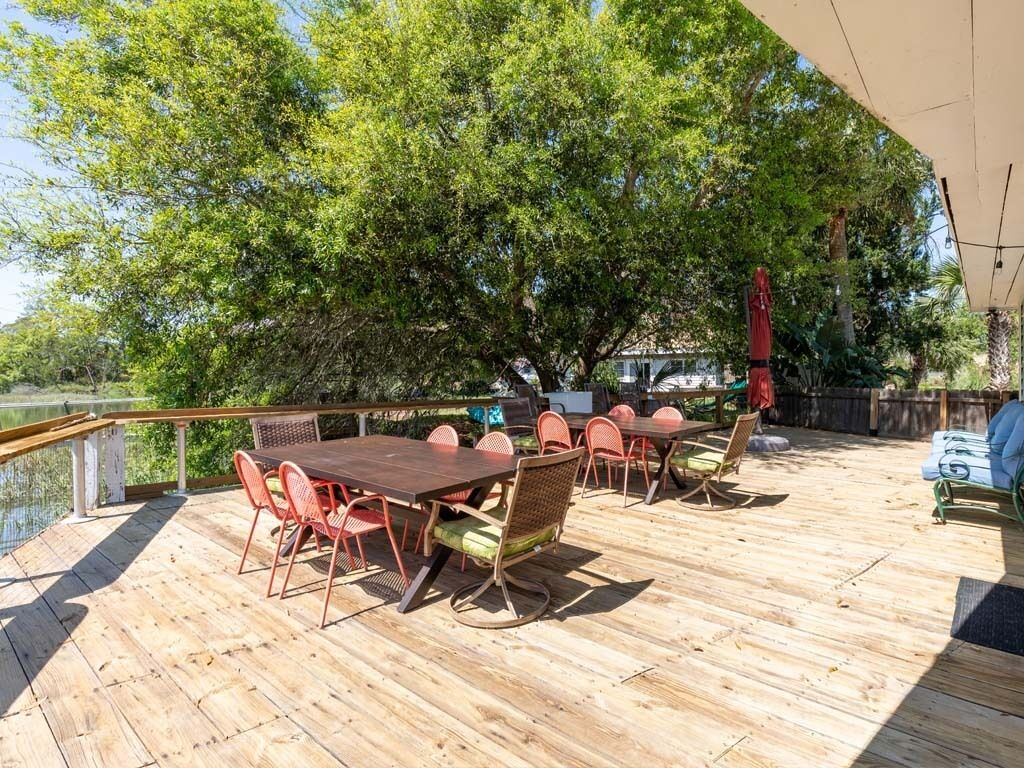 An outdoor deck with a wooden floor, surrounded by trees and a body of water.