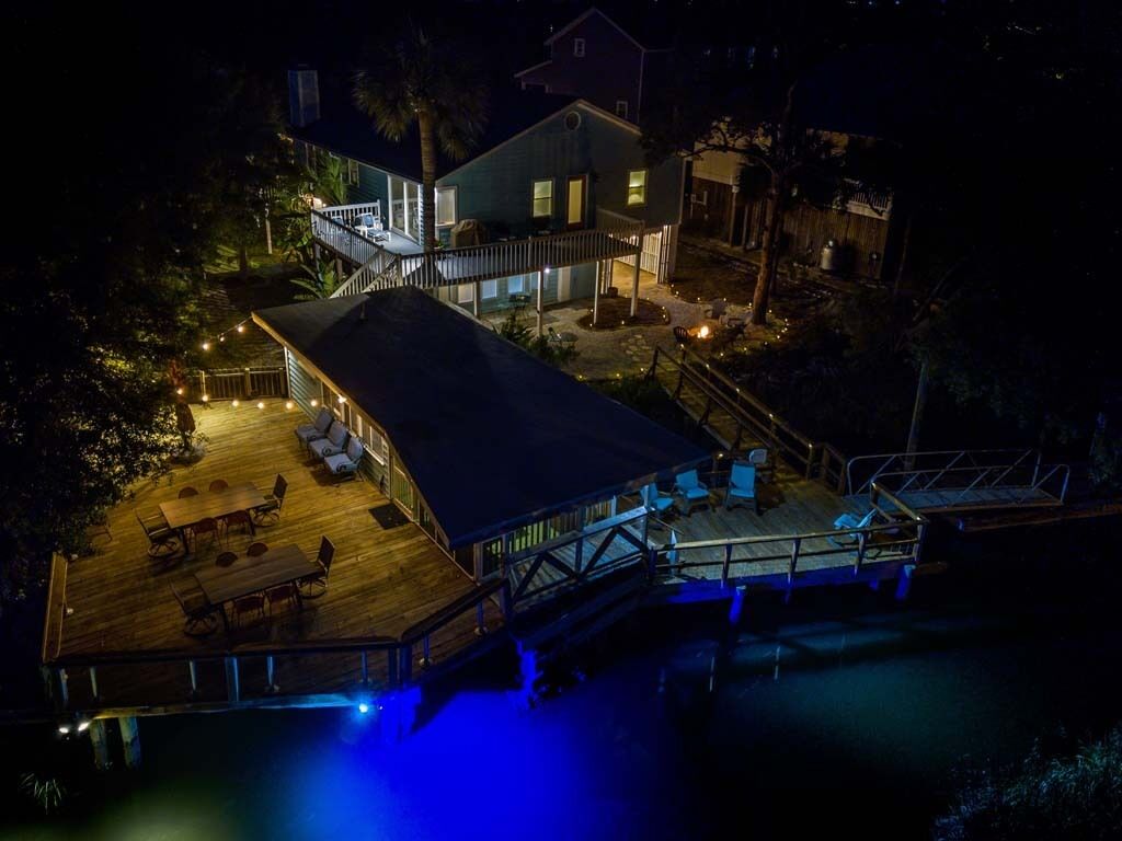 A waterfront property with a large deck, outdoor seating, and a covered area.