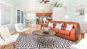 A spacious living room with a brown leather sofa, a coffee table, and patterned rugs. - All Decked Out by Tybee Vacation Rentals (Tybee Island)