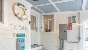 A porch with a wooden door, a set of steps, a life preserver, a sign with 'Hoffman', and an American flag. - Annas Cabana by Tybee Vacation Rentals (Tybee Island)