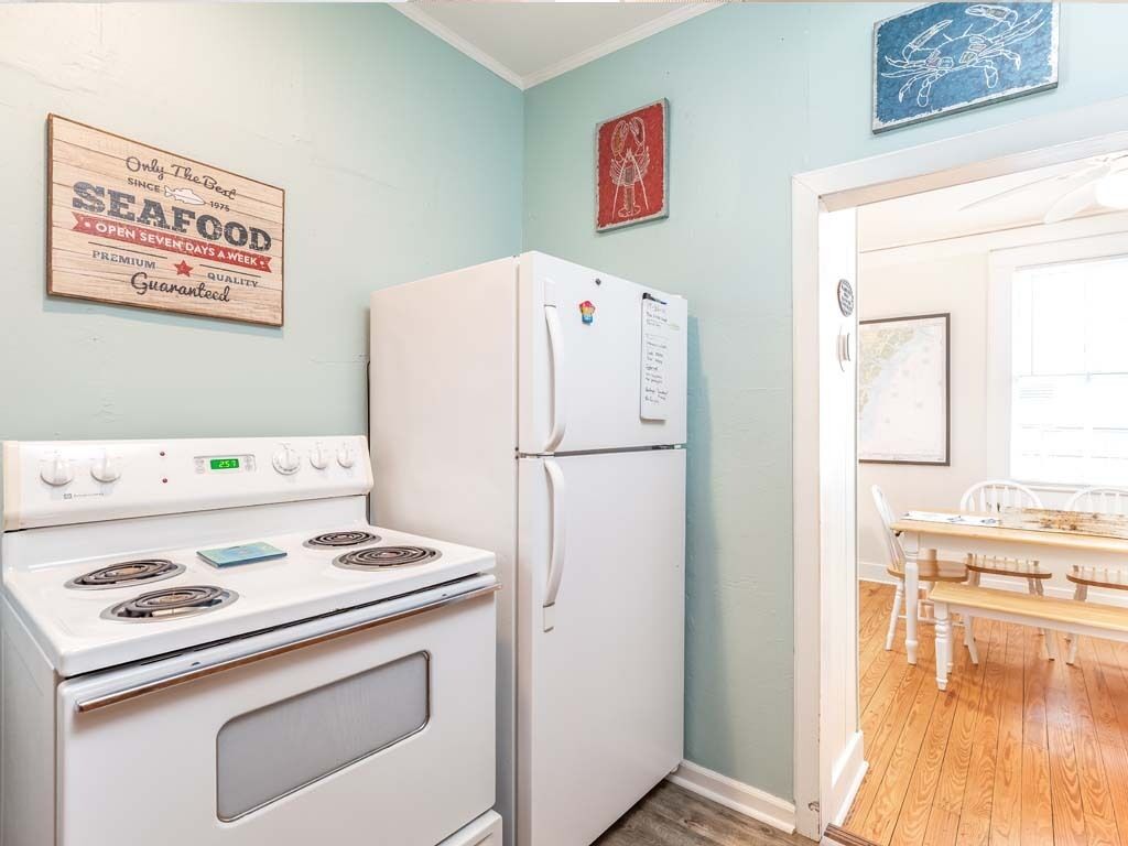 A kitchen with a white stove, refrigerator, and wooden table.