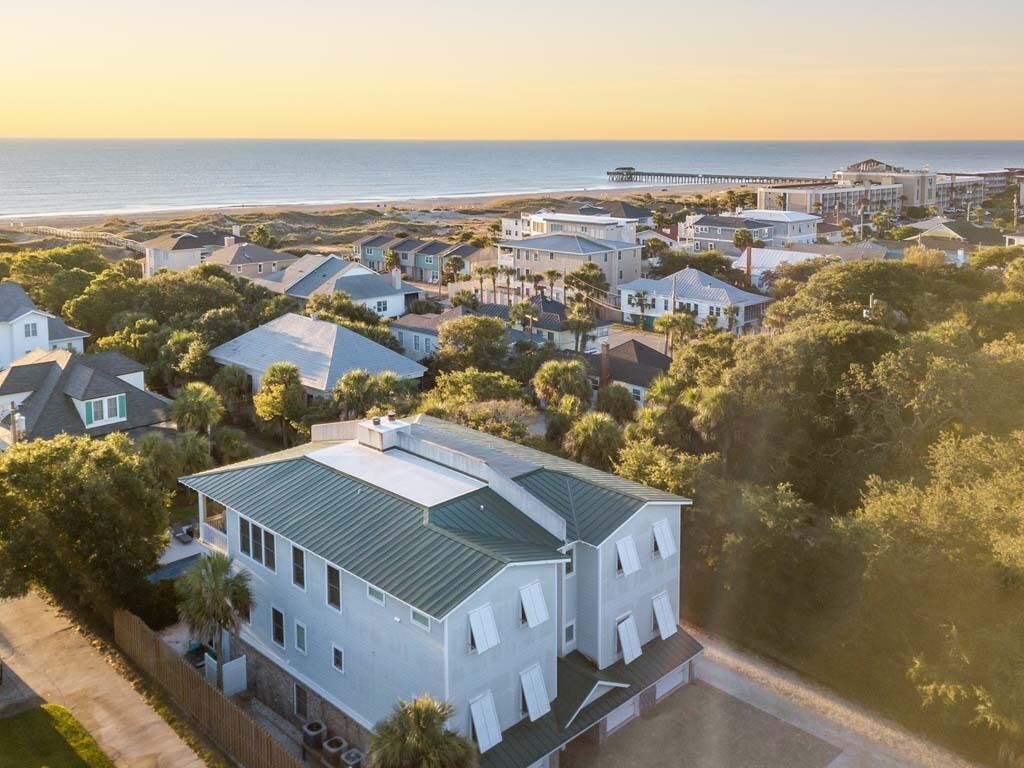 Vista aérea de una zona residencial costera con casas, un muelle y una playa.