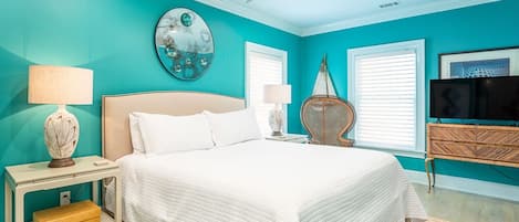A bedroom with a bed, nightstands, a ceiling fan, a TV, and a wall with a decorative mirror.