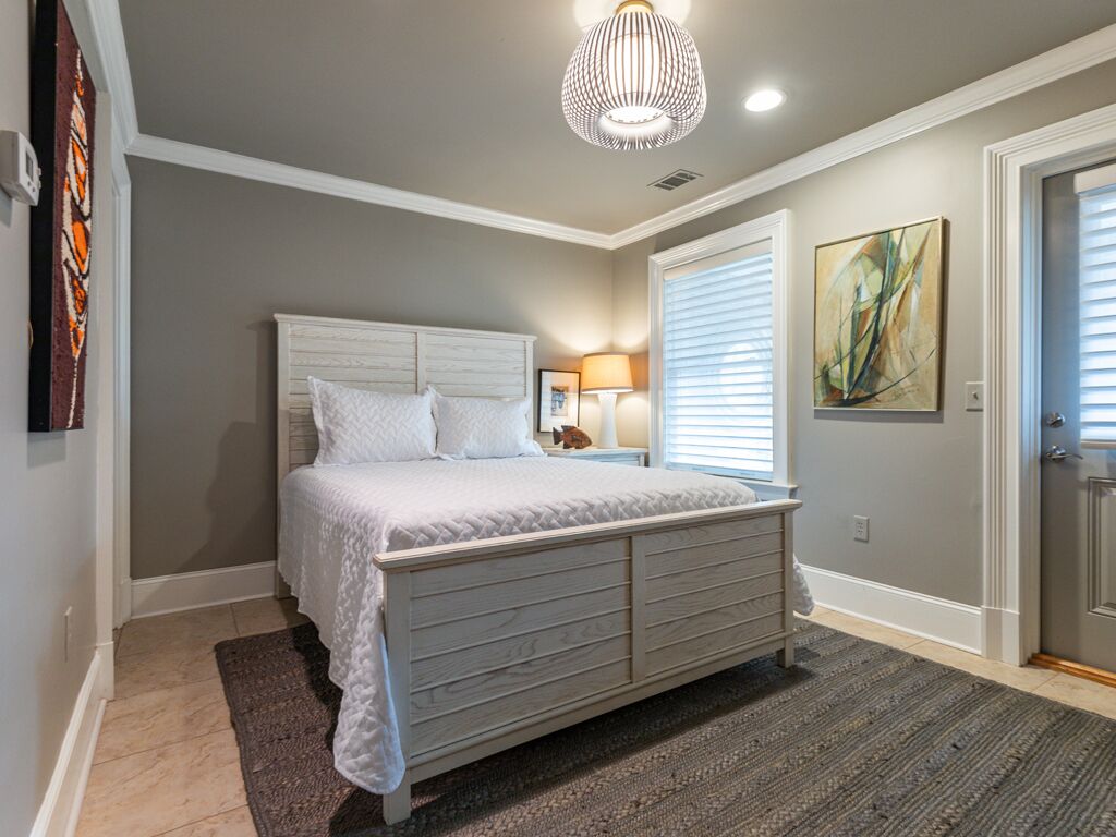 A bedroom with a bed, bedside lamp, and artwork on the wall.