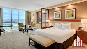 Une chambre d’hôtel avec un grand lit, un bureau, une chaise, un banc et une vue sur l’océan.