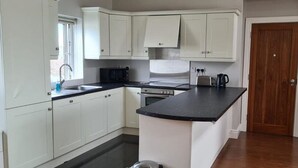 A kitchen with white cabinets, a black countertop, and a wooden door. - Carraroe Apartment 2 Modern apartment in Carraroe (Carraroe)
