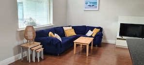 Ein Wohnzimmer mit einem blauen Sofa, einem Holztisch und einem Fernseher.