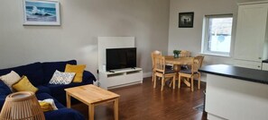 A living room with a sofa, television, and a dining area with chairs and a table.