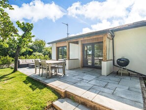 Une terrasse avec une table et des chaises, un barbecue et un espace salon abrité.