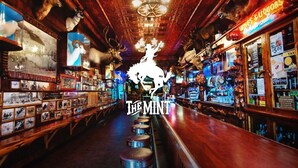 A bar with wooden decor, a neon sign, and various liquor bottles. - Wyoming Suite — Central 2BR, Sheridan WY (Sheridan)