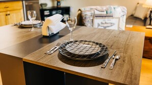 A dining area with a wooden table set for two, featuring a black and white checkered plate, a wine glass, and cutlery. - Wyoming Suite — Central 2BR, Sheridan WY (Sheridan)