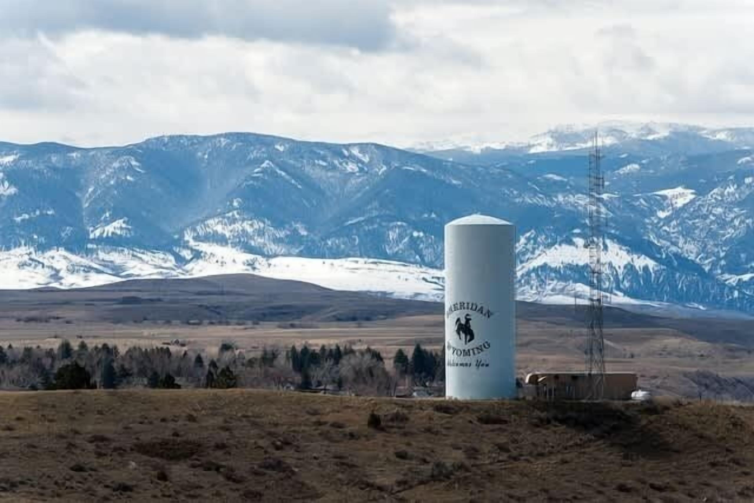 A cylindrical structure with a logo, set against a mountainous backdrop.