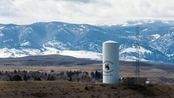 A cylindrical structure with a logo, set against a mountainous backdrop.