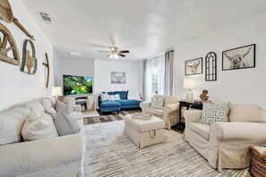 Ein Wohnzimmer mit einer Sofagarnitur, einem blauen Sofa, einem Couchtisch und einem Fernseher.