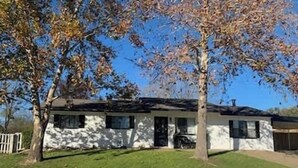Una casa de una sola planta con fachada blanca, un porche y un garaje.