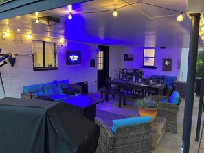Un patio al aire libre con asientos, mesas y luces colgantes.