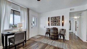 Una habitación amplia con suelo de madera, un escritorio con silla, un barril grande y un reloj fijado a la pared.