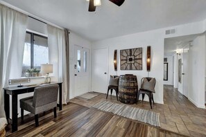 Una habitació àmplia amb terra de fusta, un escriptori amb cadira, un gran tonell i un rellotge penjat a la paret.