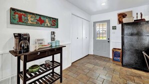 Un couloir avec un coin café, un panneau indiquant le Texas et un réfrigérateur.
