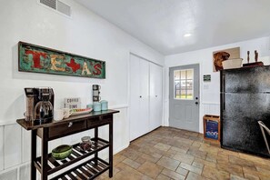 A hallway with a coffee station, a Texas sign, and a refrigerator. - Bayer Guesthaus: Hot-Tub & Fire Table (Fredericksburg)