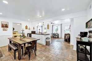 Una cocina amplia con una isla central, suelo de madera y paredes blancas.