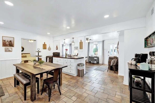 A spacious kitchen with a central island, wooden flooring, and white walls.
