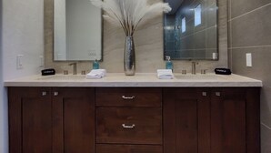 A modern bathroom with a large vanity, two mirrors, a vase with pampas grass, and a "Makeup" sign.