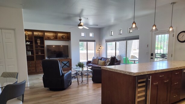 A modern kitchen with a central island, wooden cabinets, and pendant lighting.