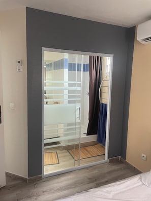 Une pièce dotée d’une porte-fenêtre coulissante donnant accès à une salle de bain, d’un lit et d’un plancher en bois.