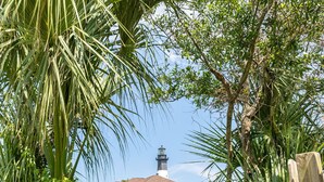 A house with a lighthouse in the background, surrounded by lush greenery. - Beach Bum Inn by Tybee Vacation Rentals (Tybee Island)