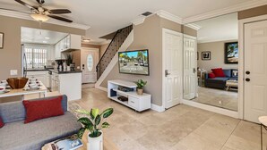 A spacious living area with a sofa, coffee table, and a TV mounted on the wall. - Spacious 3BR-  Yard - BBQ - Parking! (Costa Mesa)