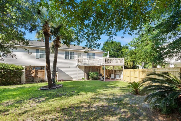 A two-story house with a covered patio and a fenced backyard.