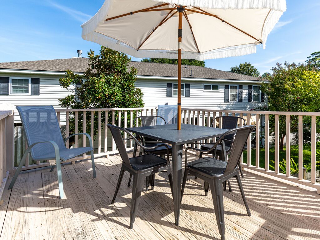 Une terrasse avec une table et des chaises, un parasol et une rambarde.