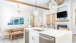 A modern kitchen with a central island, white cabinetry, and stainless steel appliances. - Big Wave by Tybee Vacation Rentals (Tybee Island)