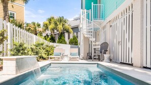 A swimming pool with a white fence, lounge chairs, and a water feature. - Big Wave by Tybee Vacation Rentals (Tybee Island)