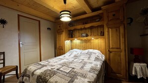 A bedroom with a bed, wooden headboard, built-in shelves, a door, and a small table with a lamp. - Ground floor, parking, tv, 62m², Arêches-Beaufort (Beaufort)