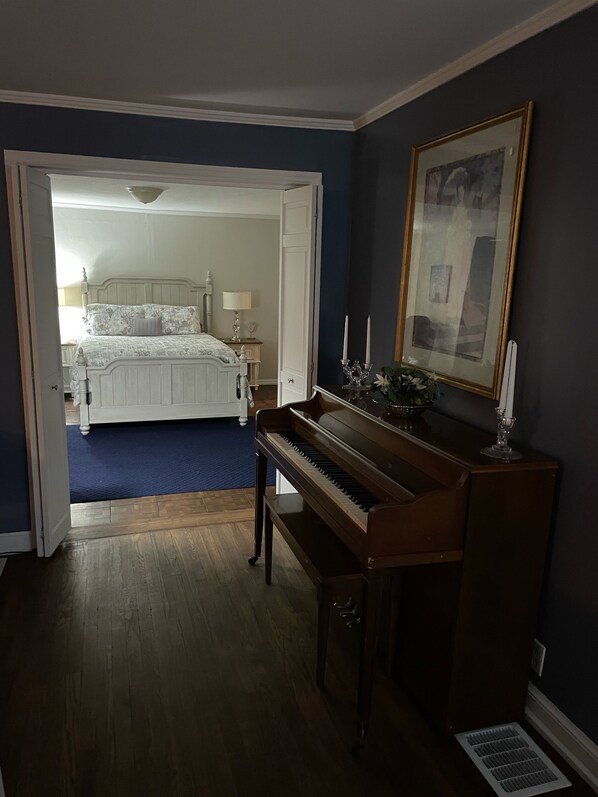 A room with a piano, a bed, and a framed picture on the wall.