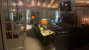 A cozy living room with a fireplace, leather sofa, and a television mounted on the wall.