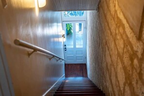 Una escalera que lleva a una puerta con vistas al verdor exterior.