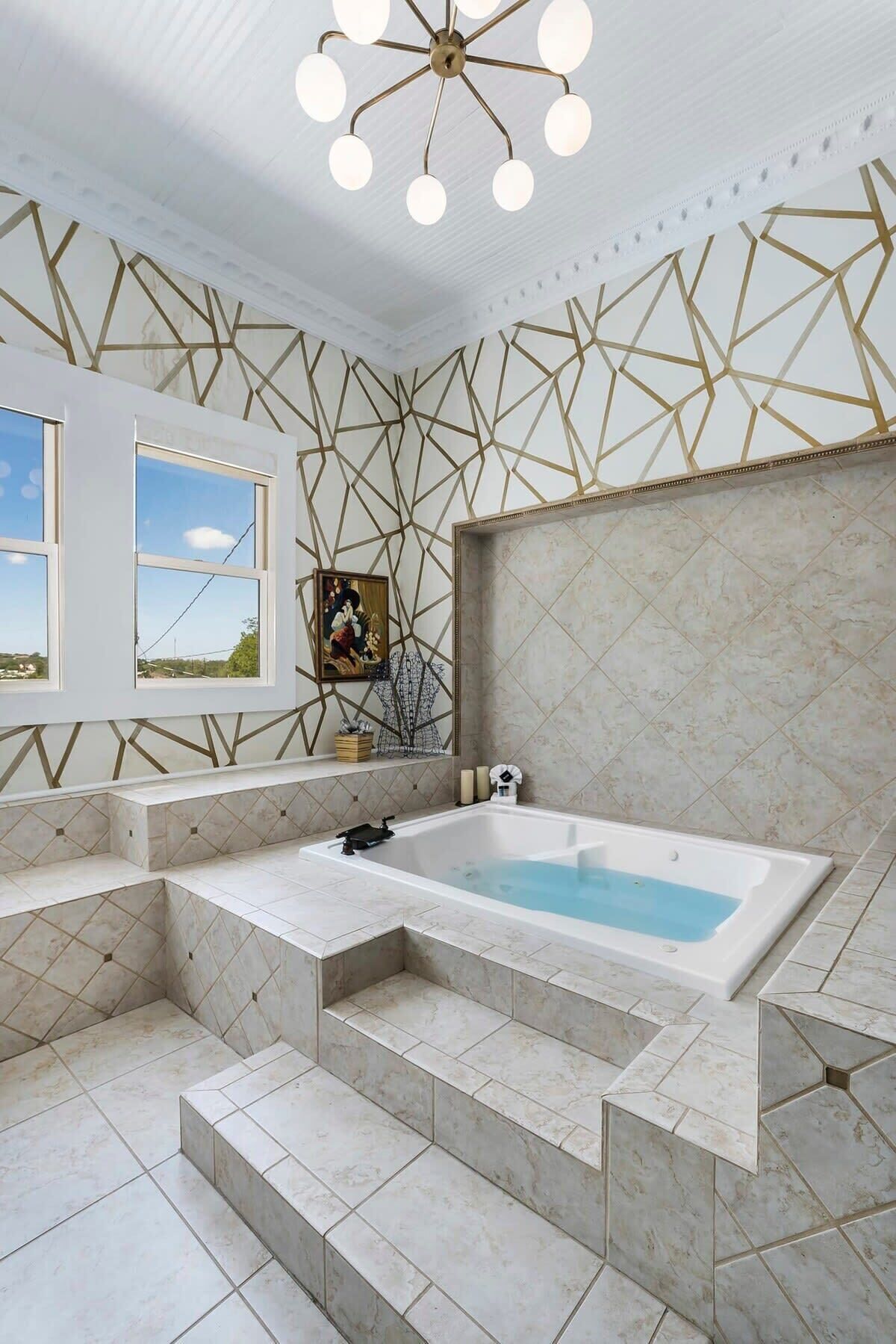 A bathroom with a freestanding bathtub, geometric wall patterns, and a window with a view.