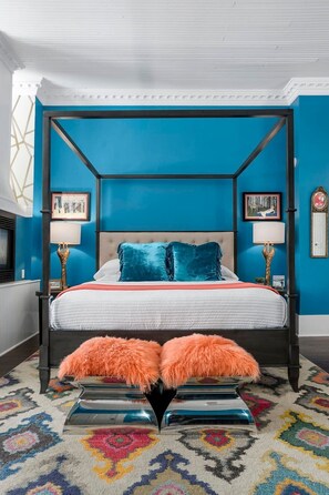 A four-poster bed with a white and teal color scheme, a tufted headboard, and a colorful patterned rug. - The Loft on Main St, Balcony Views, Roman bathtub! (Fredericksburg)
